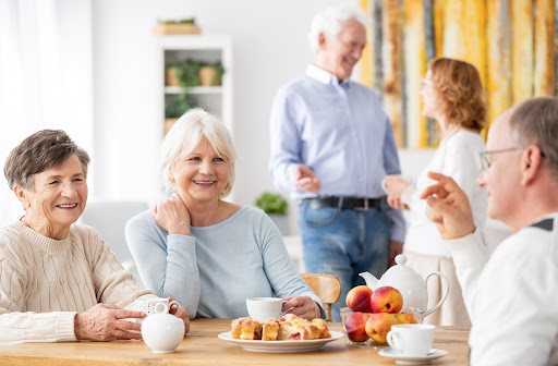 Seniors sitting around a table with friends enjoying tea and baked goods together