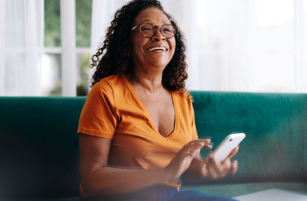 A senior sitting on their couch using an app on their phone to monitor their health and wellness.