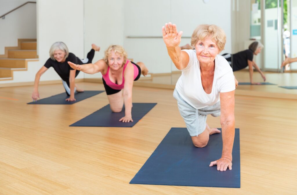 A group of senior friends in independent living participate in a yoga class at a community.