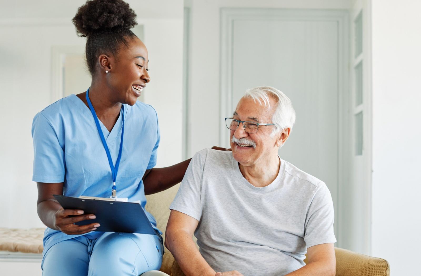 A caregiver smiles with a memory care resident while facilitating a cognitive stimulation exercise.